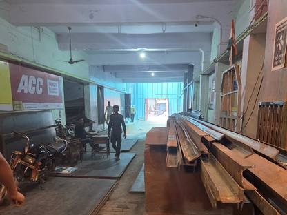 Channel lengths on a raised platform and steel plate stacked flat on the floor at Jay Shree Infra