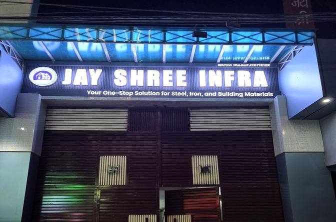 The lit board of Jay Shree Infra over two closed shutters on Meera Talkies Road in Saharsa at night