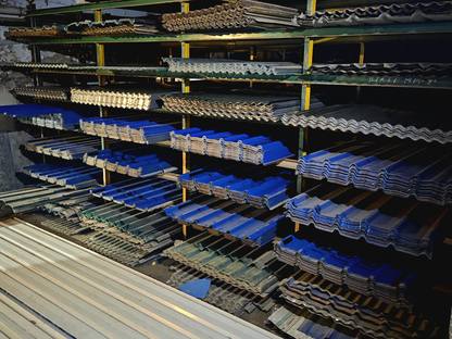 A green steel rack of roofing sheets at Jay Shree Infra: corrugated GC, tile profile and trapezoidal colour coated in blue and grey