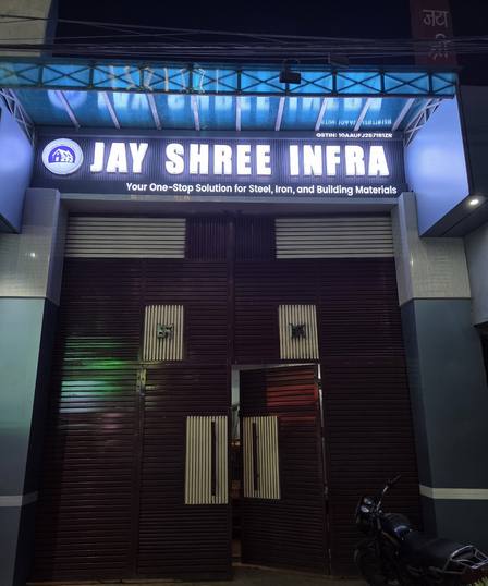 The front of Jay Shree Infra lit at night, the name board glowing over closed shutters